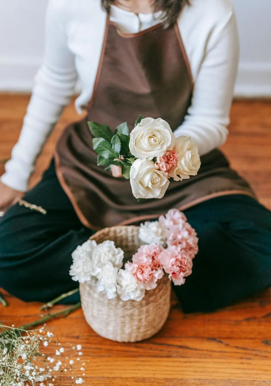 White roses held over a seagrass basket of pink and white carnations