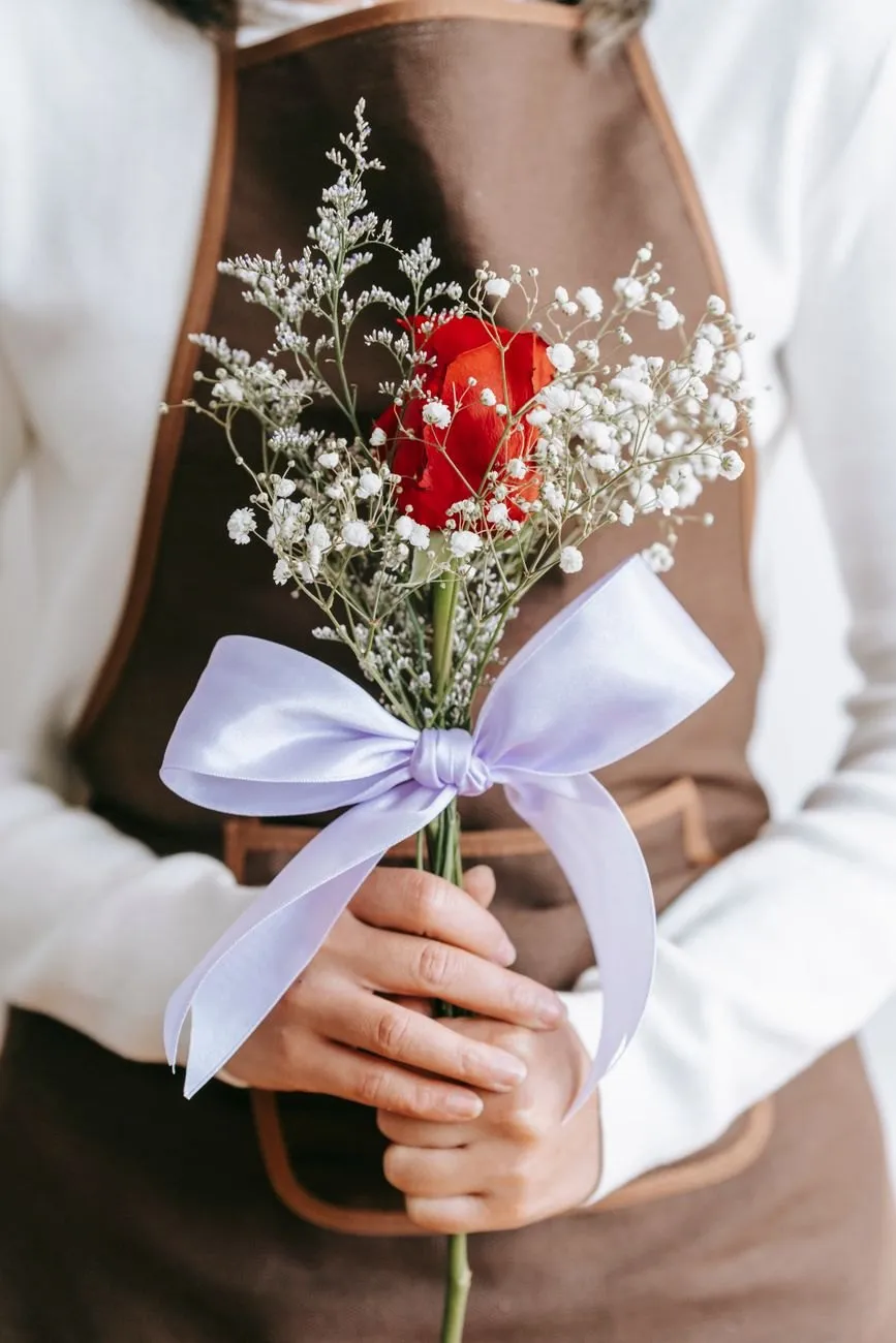 A small posy of one red rose and gypsophila tied with a lilac satin ribbon